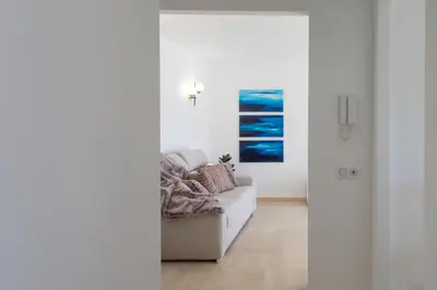 a white living room with a couch and a painting at C7 - 1 BDR Pointe Croisette 5min Sea - Parking, AC & Terrace in Cannes