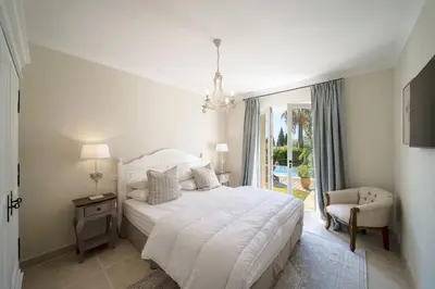 a white bedroom with a bed and a chair at REF 2135 - Cannes - Villa for rent in Cannes
