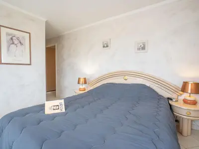 a large blue bed in a room with two lamps at Apartment Les Cascades du Lac by Interhome in Le Cannet