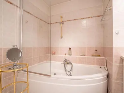 a bathroom with a tub with a shower and a mirror at Apartment Les Cascades du Lac by Interhome in Le Cannet