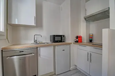 a kitchen with white cabinets and a sink and a microwave at Appartement plein centre proche Palais et plages in Cannes