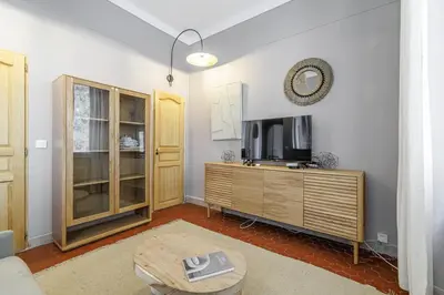 a living room with a tv and a wooden cabinet at L'Échappée Cannoise Forville in Cannes