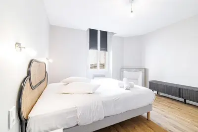 a white bedroom with a bed and a mirror at L'Échappée Cannoise Forville in Cannes