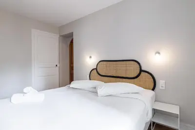 a white bedroom with a large bed with white sheets at L'Échappée Cannoise Forville in Cannes