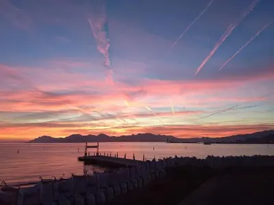 a sunset over a body of water with a pier at STUDIO VILLA VIANNEY in Cannes