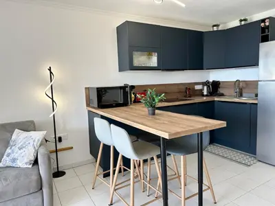 a kitchen with blue cabinets and a wooden table and chairs at Villa FRANCIA bat Van Gogh in Cannes