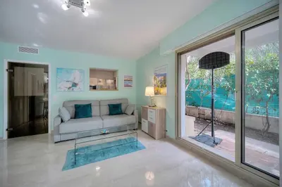 a living room with a couch and a large window at Immogroom - Quiet T2 - Garden level - AC - Wifi in Cannes