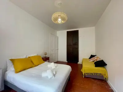 a bedroom with a white bed and a yellow couch at Le Zeus - Cannes Villa St Henri seafront unique 2bedrooms in Cannes