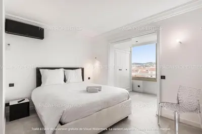 a white bedroom with a bed and a chair at Cannes appart 3 chambres luxe - Impératrice in Cannes
