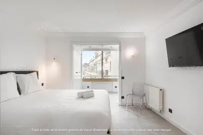 a white bedroom with a bed and a flat screen tv at Cannes appart 3 chambres luxe - Impératrice in Cannes