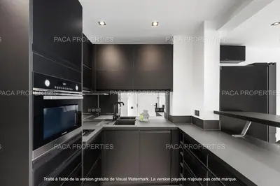 a kitchen with black and white cabinets and appliances at Cannes appart 3 chambres luxe - Impératrice in Cannes