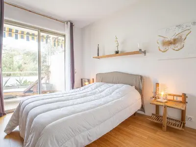 a white bedroom with a large bed and a window at Apartment Les Aliscamps by Interhome in Cannes