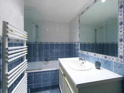 a blue tiled bathroom with a sink and a mirror at Apartment Cannes Bay-2 by Interhome in Cannes