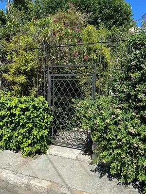 a metal gate in a garden with flowers at Résidence PARADIS BLEU - Appt 3P in Cannes