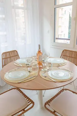 a wooden table with plates and wine glasses on it at Le Maubourg - Hypercentre - 150m Croisette - AC in Cannes