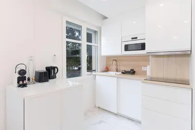 a white kitchen with white cabinets and a window at Le Maubourg - Hypercentre - 150m Croisette - AC in Cannes