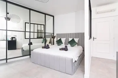 a bedroom with a white bed with a large mirror at Le Joffre - Hypercentre - 200m Palais - AC in Cannes