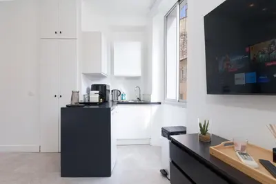 a kitchen with white walls and a black refrigerator at Le Joffre - Hypercentre - 200m Palais - AC in Cannes