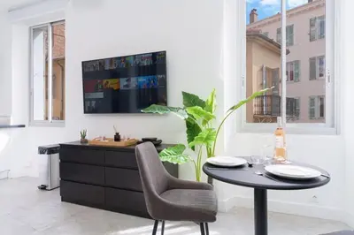 a dining room with a table and a tv on a wall at Le Joffre - Hypercentre - 200m Palais - AC in Cannes