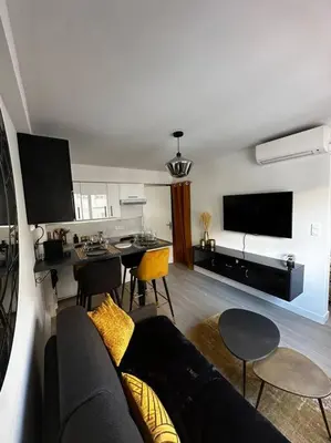 a living room with a couch and a table with chairs at Joli F2, 7 min de la gare in Cannes
