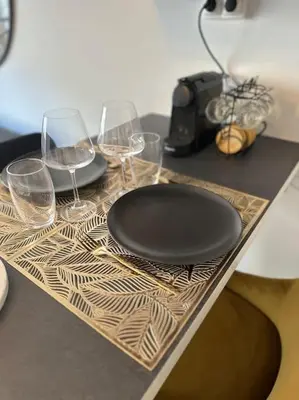 a table with a black plate and wine glasses at Joli F2, 7 min de la gare in Cannes