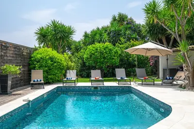 a swimming pool with chairs and an umbrella at CANNES VILLA: 15 mins walk to beach & centre in Cannes
