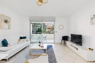 a white living room with a couch and a tv at Fleury Home YourHostHelper in Cannes