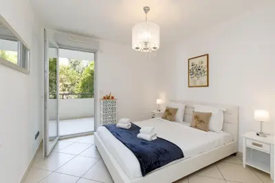 a white bedroom with a large bed and a balcony at Fleury Home YourHostHelper in Cannes