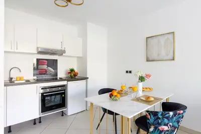a white kitchen with a white table and chairs at Fleury Home YourHostHelper in Cannes