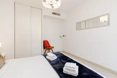 a white bedroom with a bed and a red chair at Fleury Home YourHostHelper in Cannes