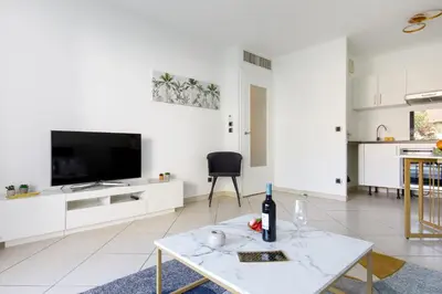 a white living room with a tv and a table at Fleury Home YourHostHelper in Cannes