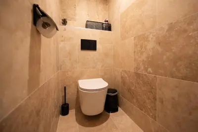 a bathroom with a toilet and a tiled wall at Palazzio T3 design près des plages et du Palais in Cannes