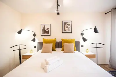 a bedroom with a large white bed with yellow pillows at Palazzio T3 design près des plages et du Palais in Cannes