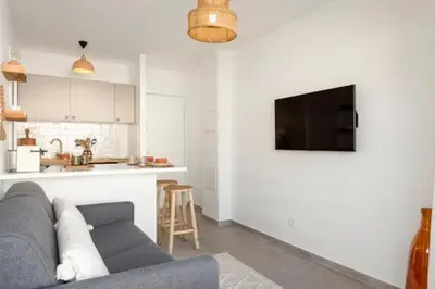 a living room with a gray couch and a kitchen at Appartement Cannes 1 chambre - QG in Cannes