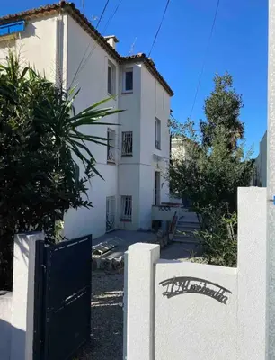 a white house with a black gate in front of it at Only 60m to the beach, 2 bedroom cozy apartment, 80m2 big garden, very central in Cannes