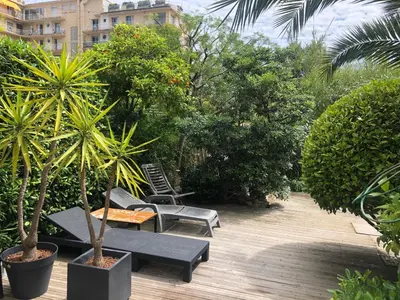 a patio with a table and chairs and trees at Only 60m to the beach, 2 bedroom cozy apartment, 80m2 big garden, very central in Cannes