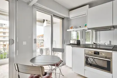 a kitchen with a table and a table and a counter at Superbe studio avec terrasse à 10 min de la plage in Cannes