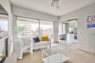 a living room with a white couch and a glass table at Superbe studio avec terrasse à 10 min de la plage in Cannes
