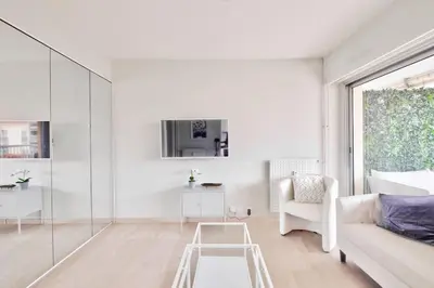 a white living room with a white couch and a table at Superbe studio avec terrasse à 10 min de la plage in Cannes