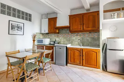 a kitchen with wooden cabinets and a table and chairs at Charming apartment heart of Le Suquet in Cannes