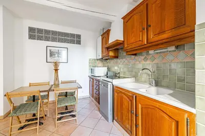a kitchen with wooden cabinets and a sink and a table at Charming apartment heart of Le Suquet in Cannes