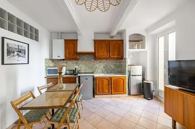 a kitchen with wooden cabinets and a table with chairs at Charming apartment heart of Le Suquet in Cannes
