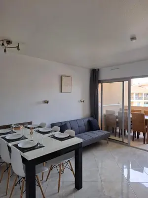 a living room with a table and a blue couch at Appartement 3 pièces, proche plage et cannes in Cannes