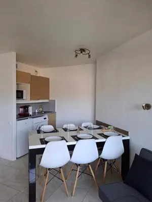 a kitchen with a dining room table and white chairs at Appartement 3 pièces, proche plage et cannes in Cannes