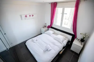 a small bedroom with a white bed with pink curtains at Comfort 6 People Apartment by Connexion in Cannes