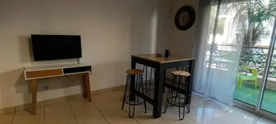 a living room with a table and stools and a television at Les Jardins de Louis in Cannes