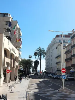 a busy city street with buildings and palm trees at Gray d'Albion - Cannes Rue d'Antibes - 2 Minutes walk from Beach, Palais des Festivals, Boulevard de la Croisette - Free Parking in Cannes