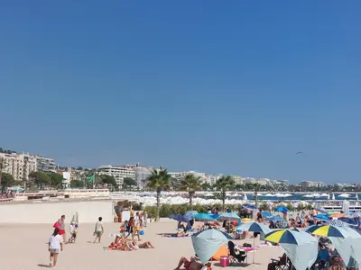 a group of people on a beach with umbrellas at Gray d'Albion - Cannes Rue d'Antibes - 2 Minutes walk from Beach, Palais des Festivals, Boulevard de la Croisette - Free Parking in Cannes