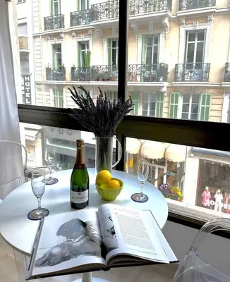 a table with a book and wine glasses and a window at Gray d'Albion - Cannes Rue d'Antibes - 2 Minutes walk from Beach, Palais des Festivals, Boulevard de la Croisette - Free Parking in Cannes