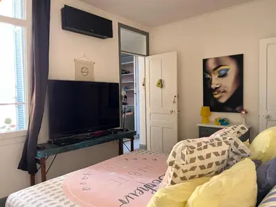 a bedroom with a television and a table with a bed at Appart'hôtel Art Deco in Cannes
